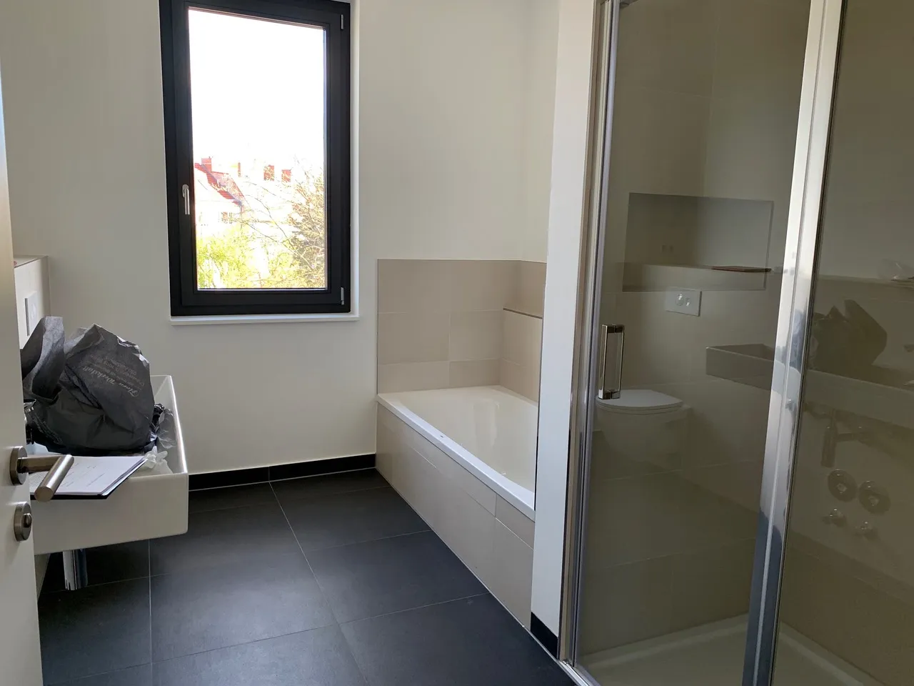 Modernes Badezimmer mit Badewanne, bodengleicher Dusche und dunklen Bodenfliesen