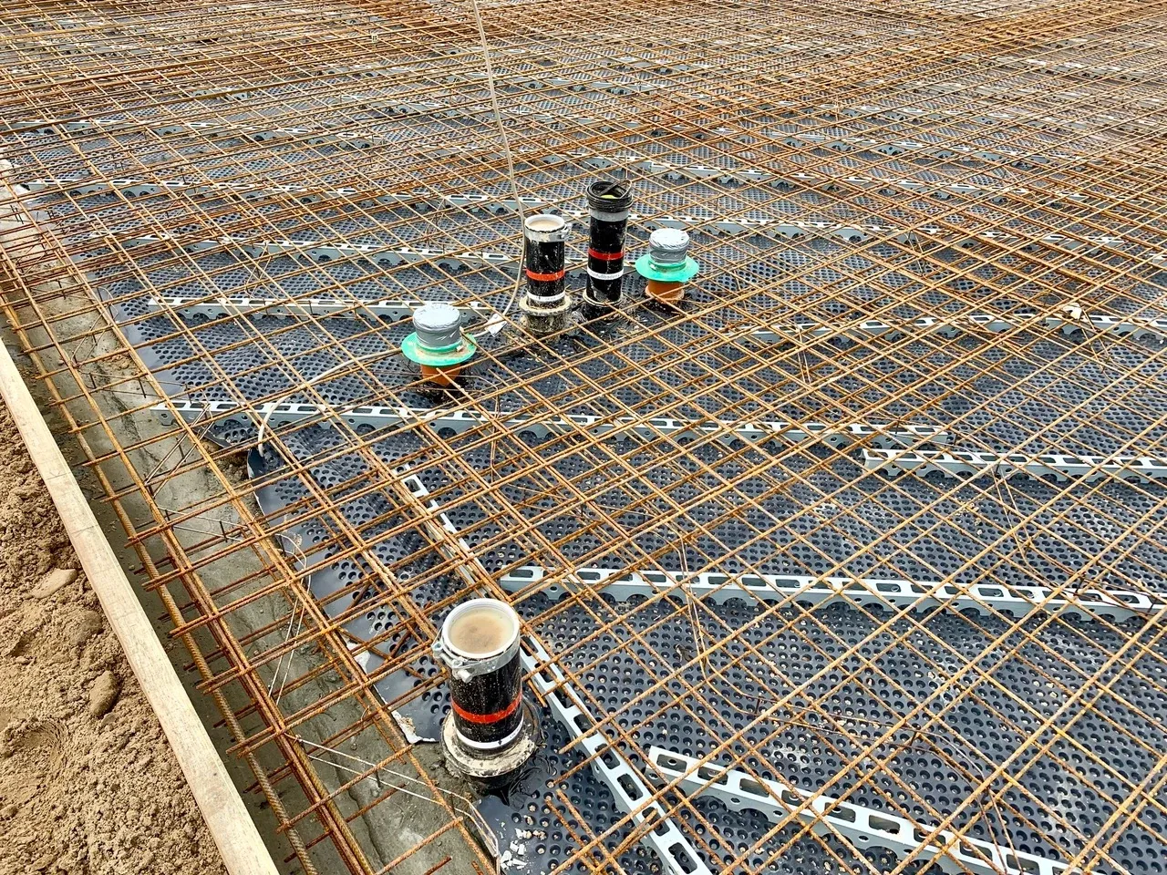 Bewehrungskorb der Bodenplatte mit Leerrohren und Steigleitungen für Hausinstallationen