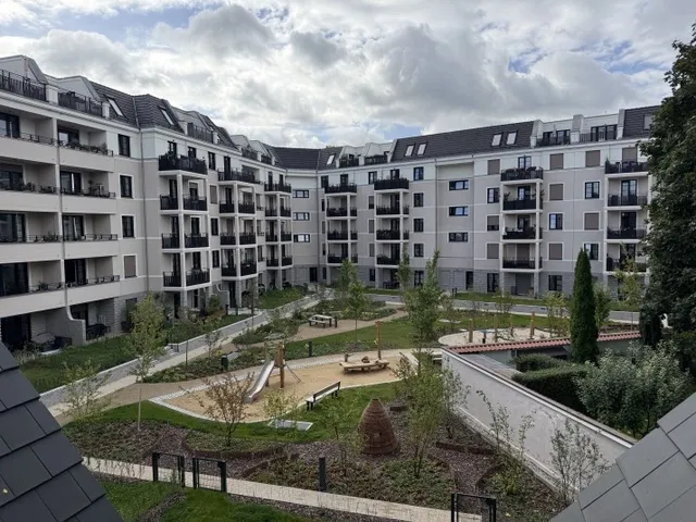 Begrünter Innenhof mit Wegen, Spielplatz und neu angelegten Bäumen im Wohnensemble CÖ in Berlin-Köpenick, umgeben von mehrgeschossigen Wohngebäuden