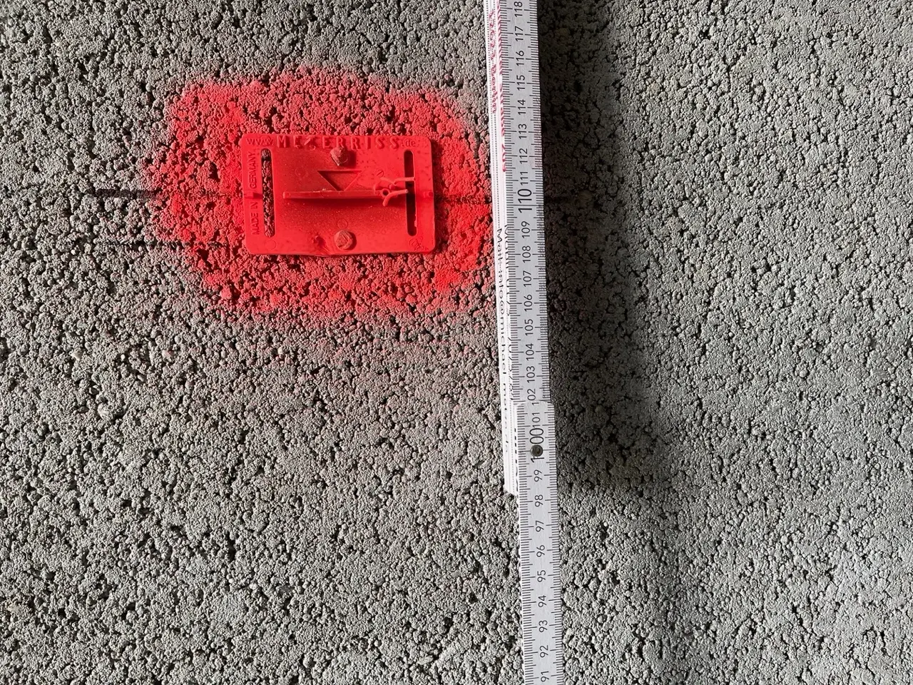 Messung an einer Wand auf der Baustelle — der Meterriss als zentraler Hoehenbezugspunkt im Innenausbau