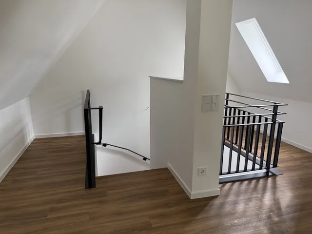 Treppenaufgang im Dachgeschoss des besichtigten Stadthauses mit Holzoptik-Boden, weißer Dachschräge und Dachflächenfenster